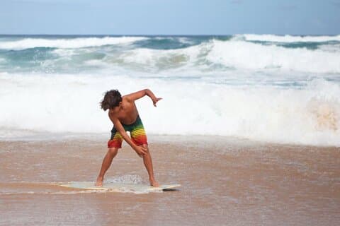 Skimboarding med en ungdomsklubstifter med tilføjelse til børn