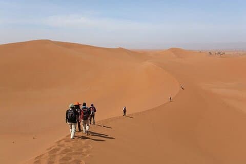 Voyage à pied au coucher du soleil dans les dunes de l'Erg Chebbi, avec un guide local.