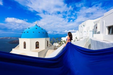 Flygande klänning Fotografering i Santorini Blue Dome Church